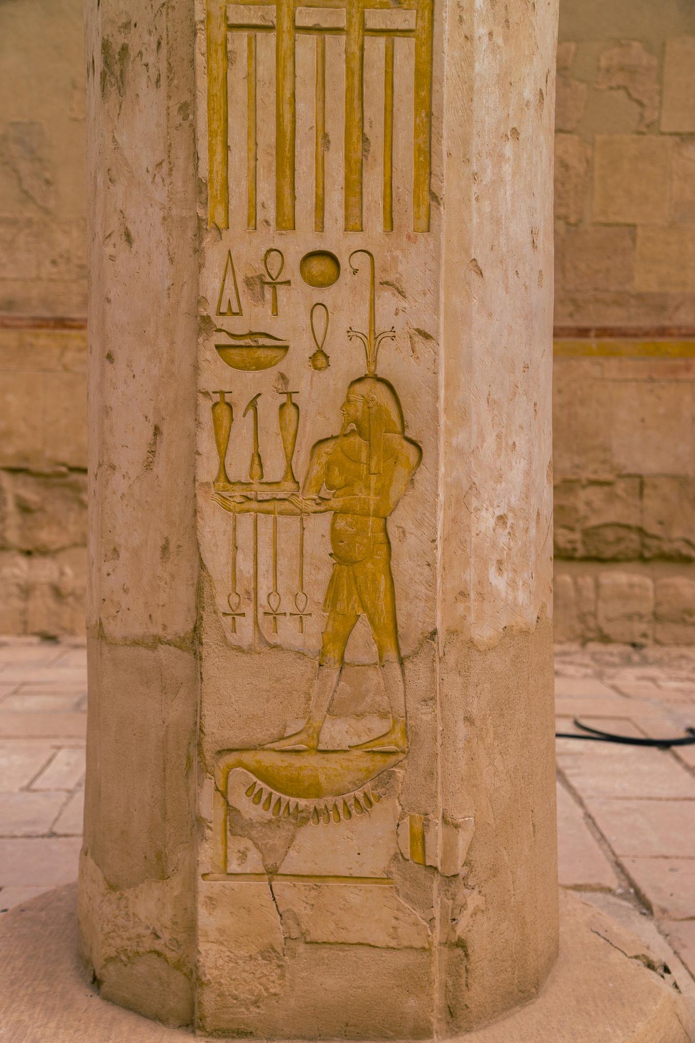 Painted relief of offering bearer with hieroglyphs carved into temple column