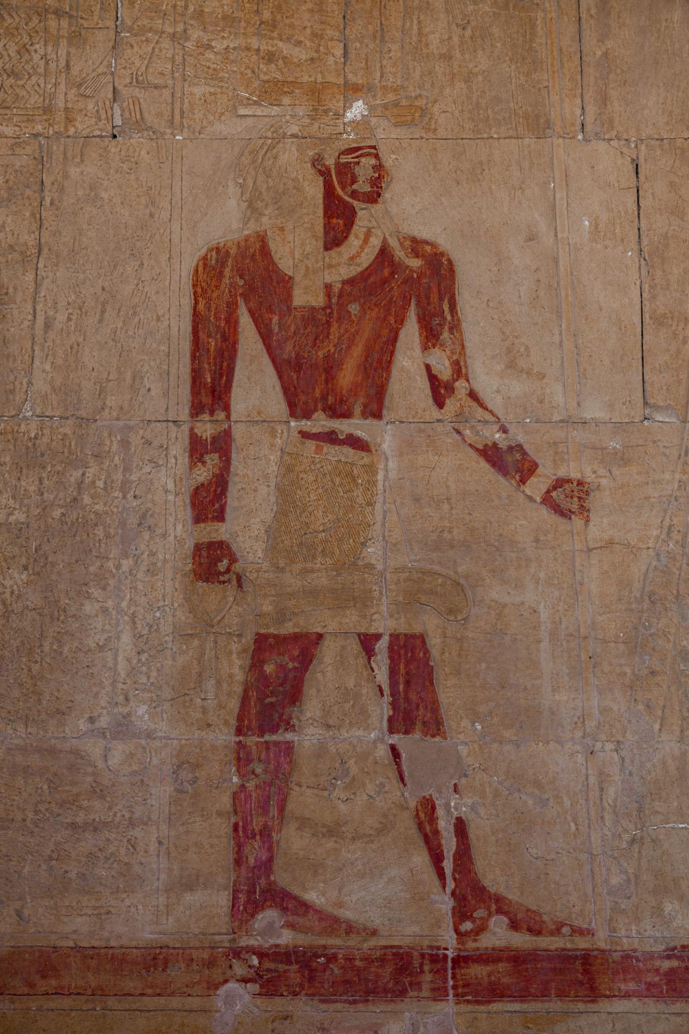Faded red-painted mural of standing figure on interior wall of Hatshepsut Temple