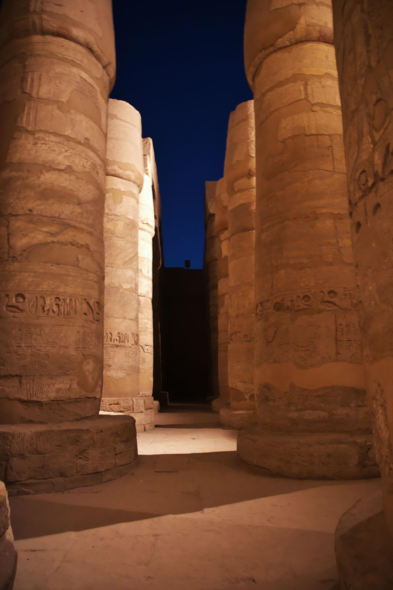 Massive hieroglyphic columns lit at night inside Karnak's Hypostyle Hall