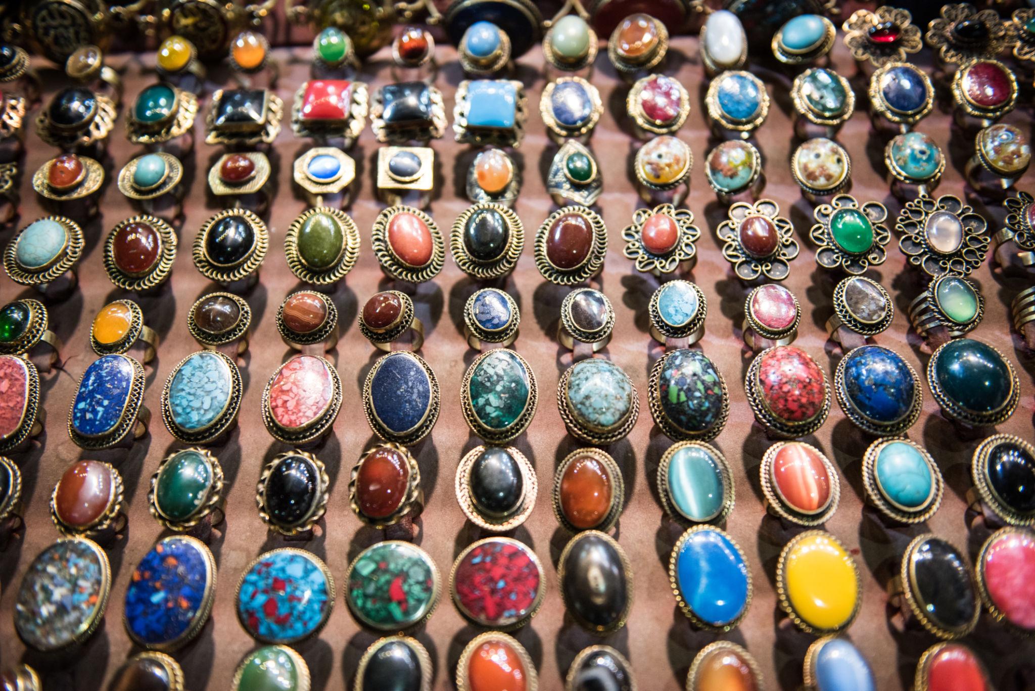 Rows of vibrant gemstone rings in gold settings displayed at Khan el-Khalili bazaar