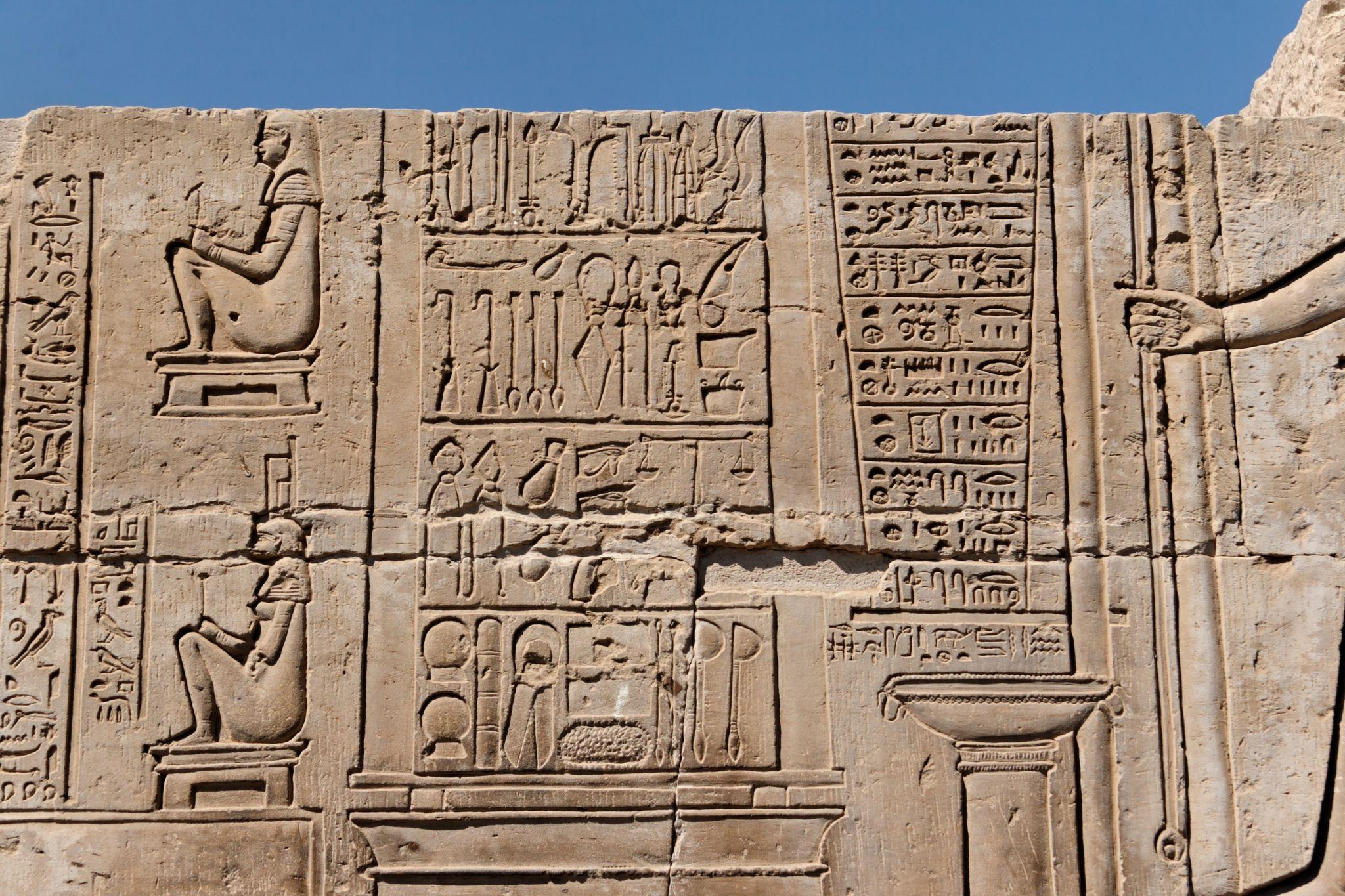 Wall relief of seated deities surrounded by columns of hieroglyphic inscriptions.