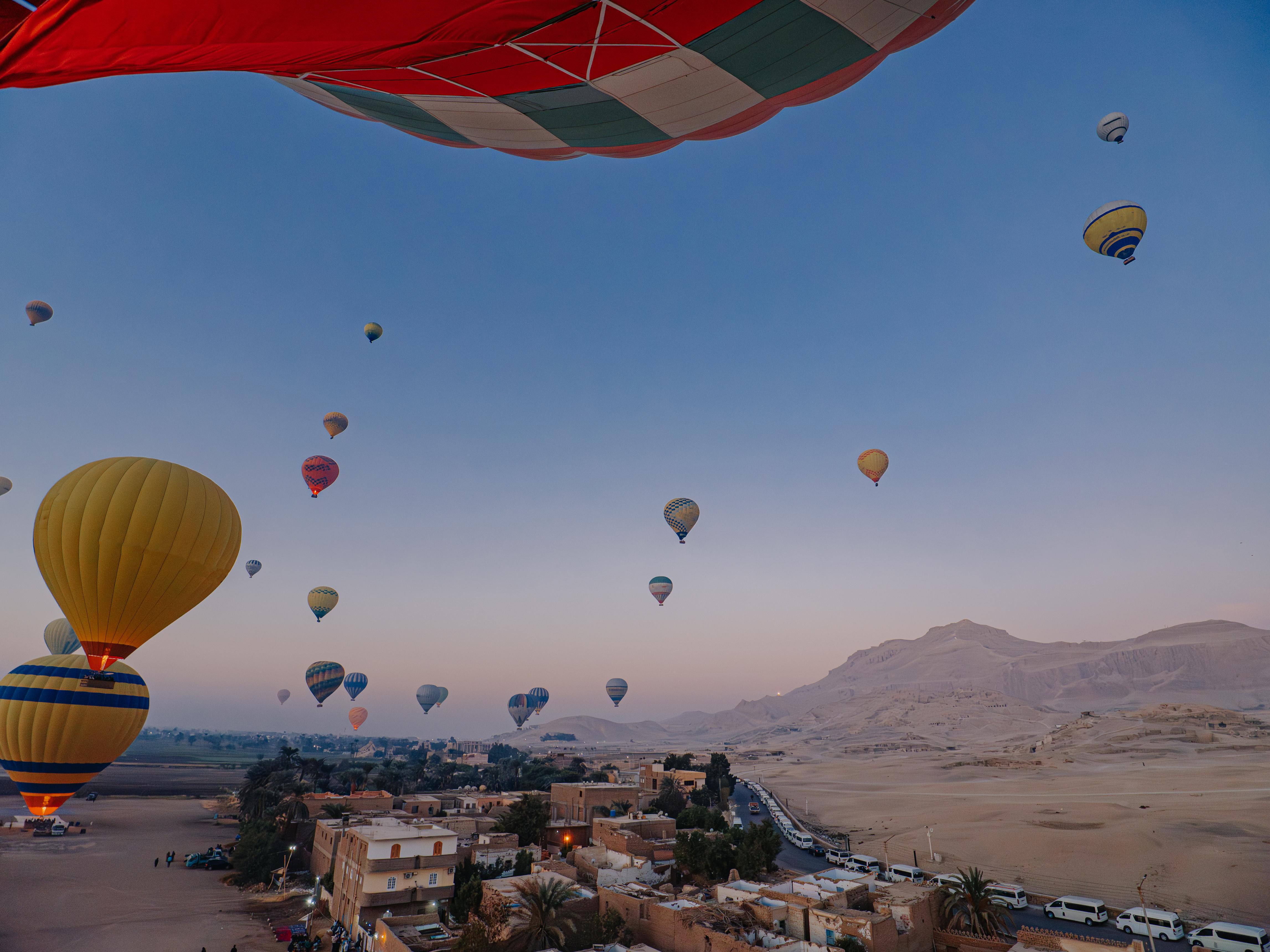 Passenger view from a balloon basket of many balloons ascending over Luxor's West Bank