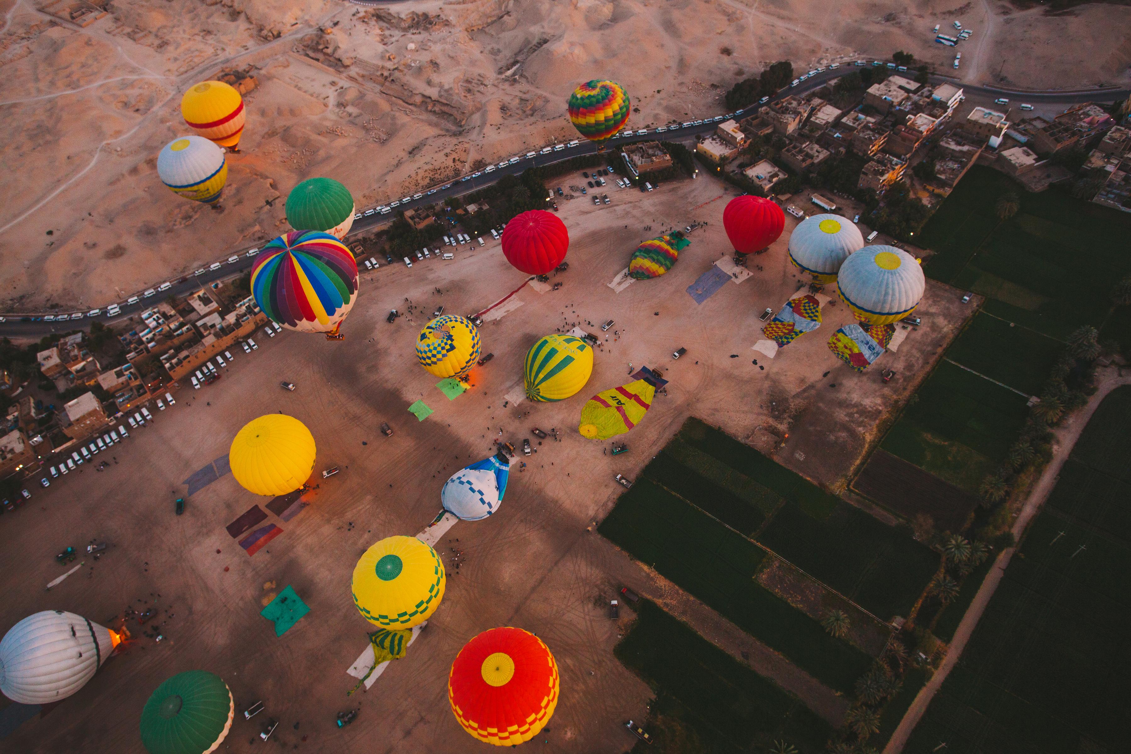 Aerial view of dozens of colorful balloons preparing on Luxor's launch field at dawn