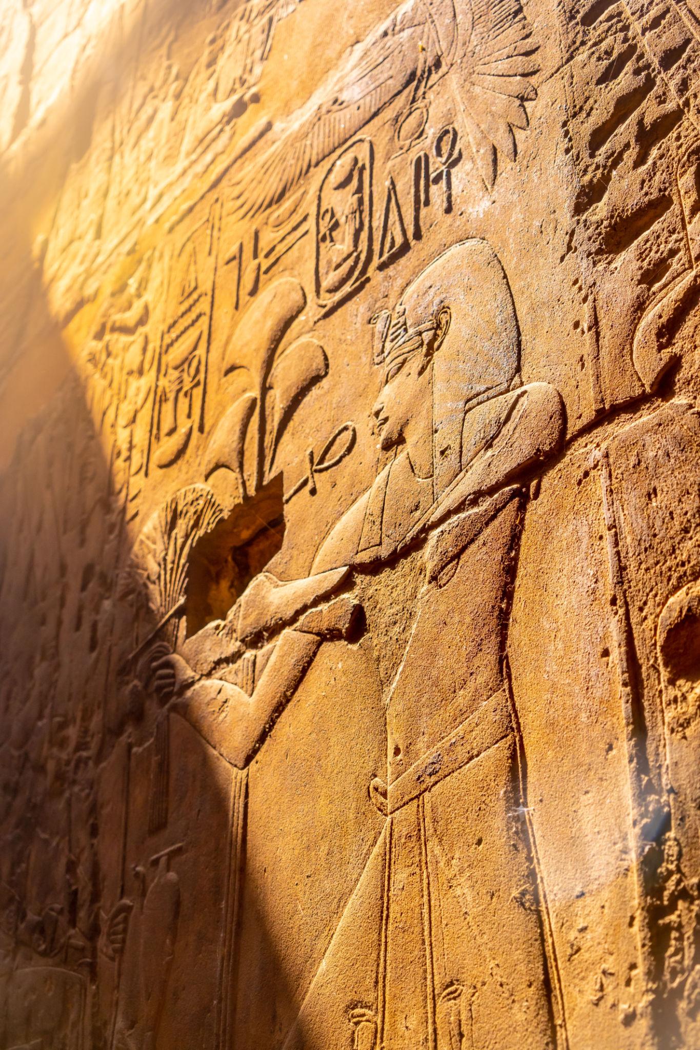 Sunlit relief of an Egyptian deity carved into a Luxor Temple wall.