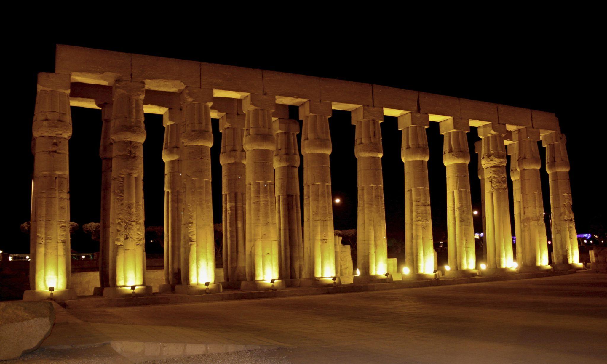 Hypostyle hall colonnade of Luxor Temple uplit against black night sky.