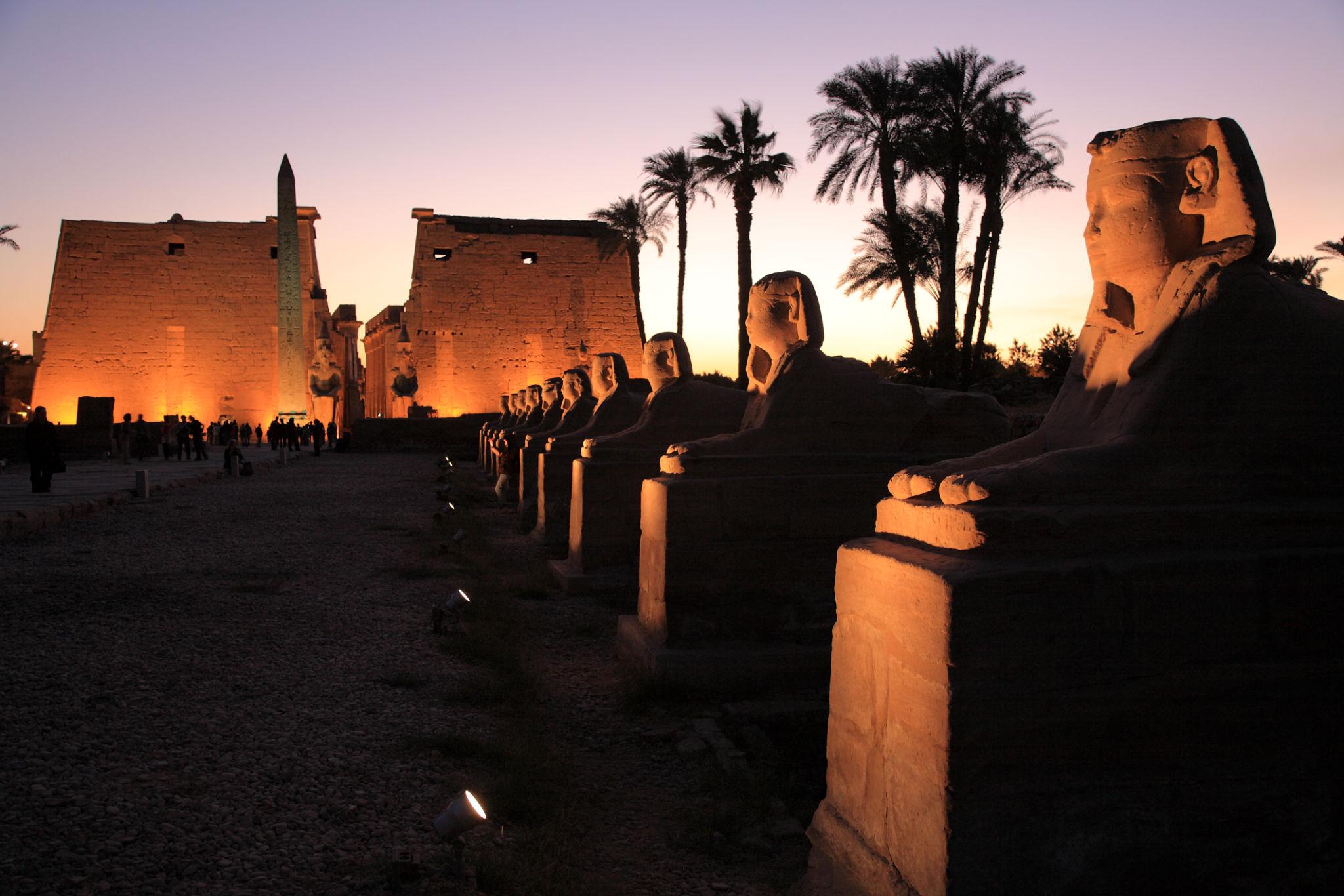 Avenue of Sphinxes leading to Luxor Temple pylon at dusk with obelisk.