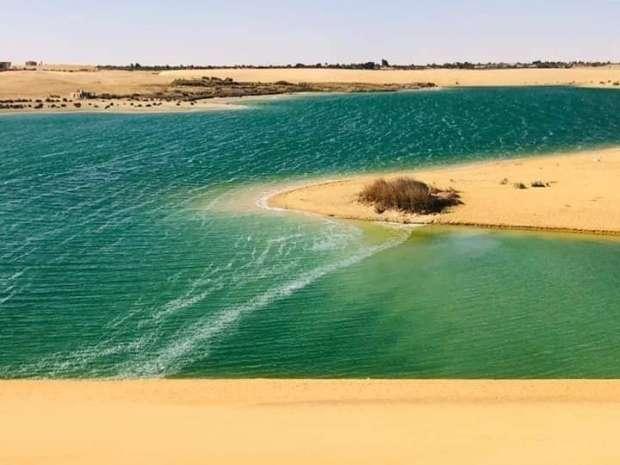 Turquoise desert lake curving between golden sand banks in Fayoum