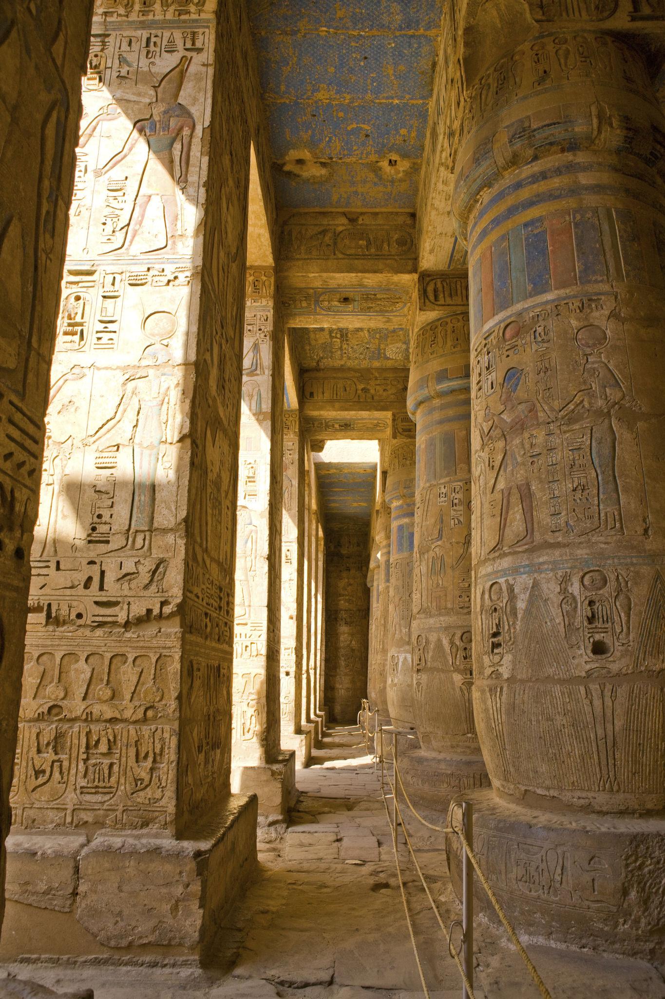 Sunlit colonnade corridor with carved pillars and painted ceiling at Medinet Habu.