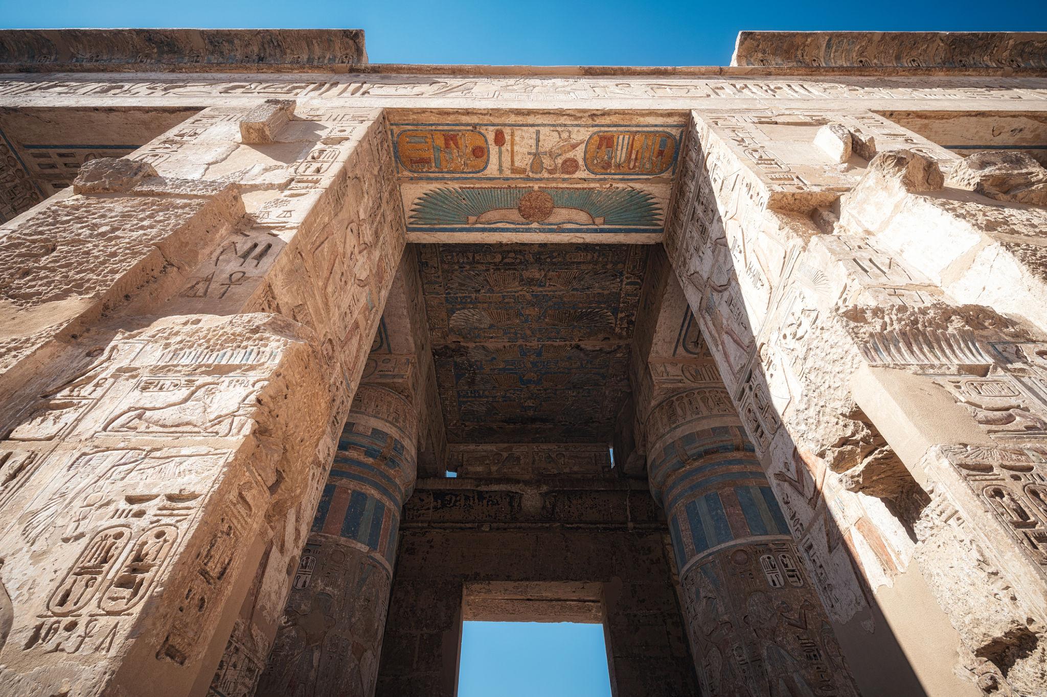 Upward view through a temple gateway showing painted lintel at Medinet Habu.