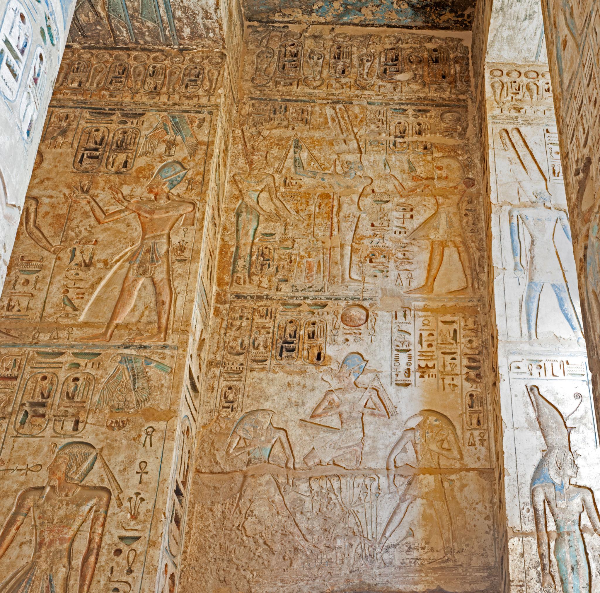 Painted wall reliefs of kings and gods inside a chapel at Medinet Habu.