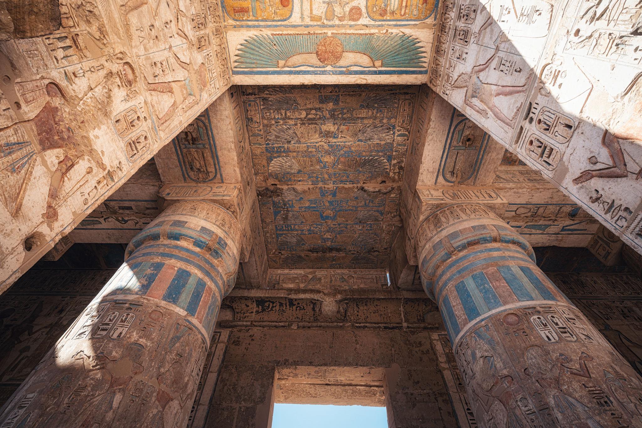 Upward view of vibrantly painted ceiling and capitals in Medinet Habu's second court.