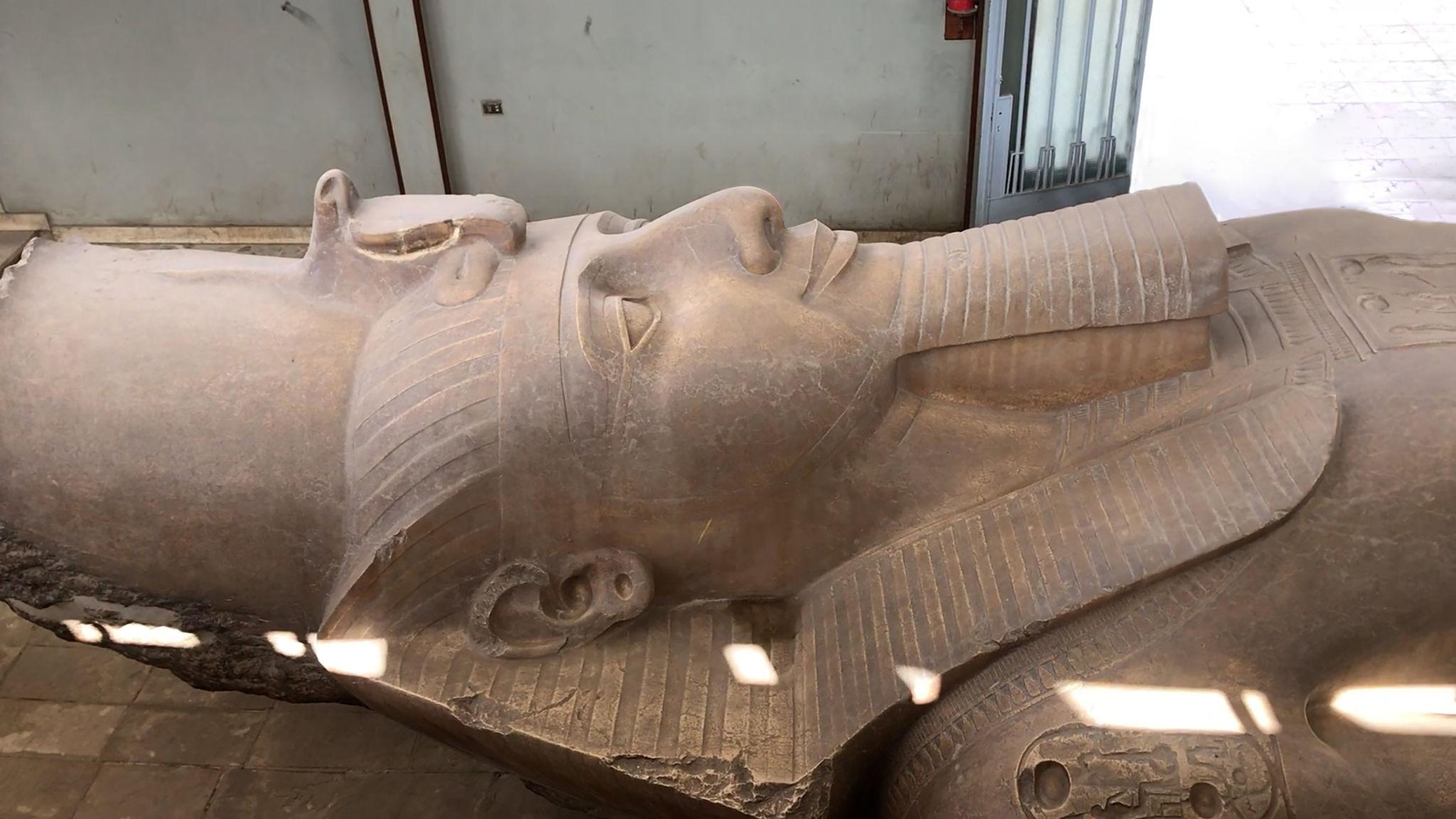Massive limestone statue of Ramesses II lying horizontally inside the NMEC museum hall