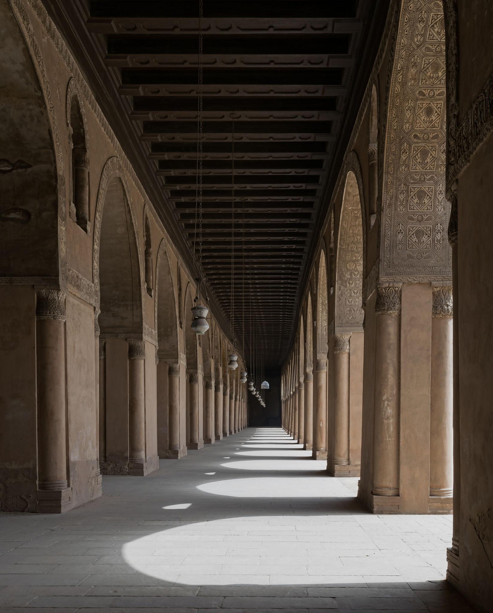 Long arched arcade of Ibn Tulun Mosque with decorated piers and hanging lamps
