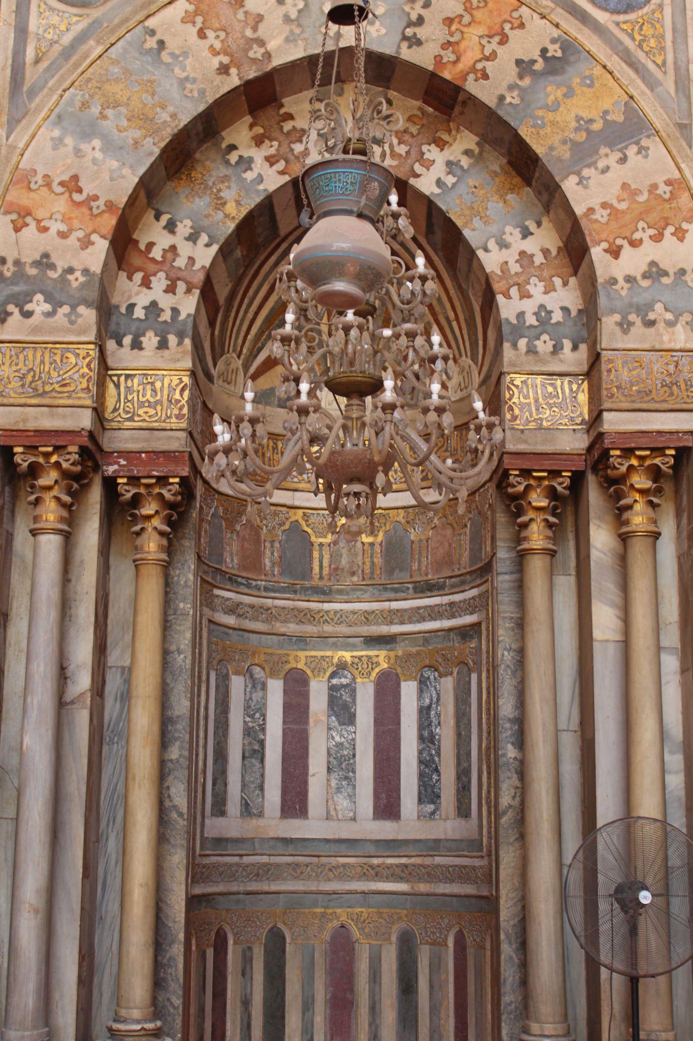 Ornate mihrab niche with marble columns and suspended brass chandelier in Mamluk style