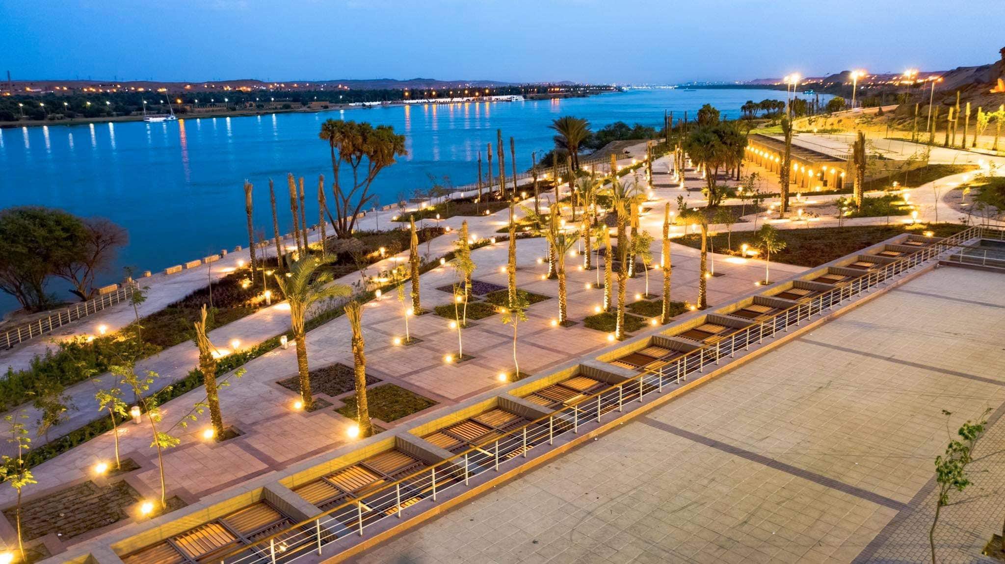 Palm-lined riverside promenade along the Aswan corniche illuminated at dusk.