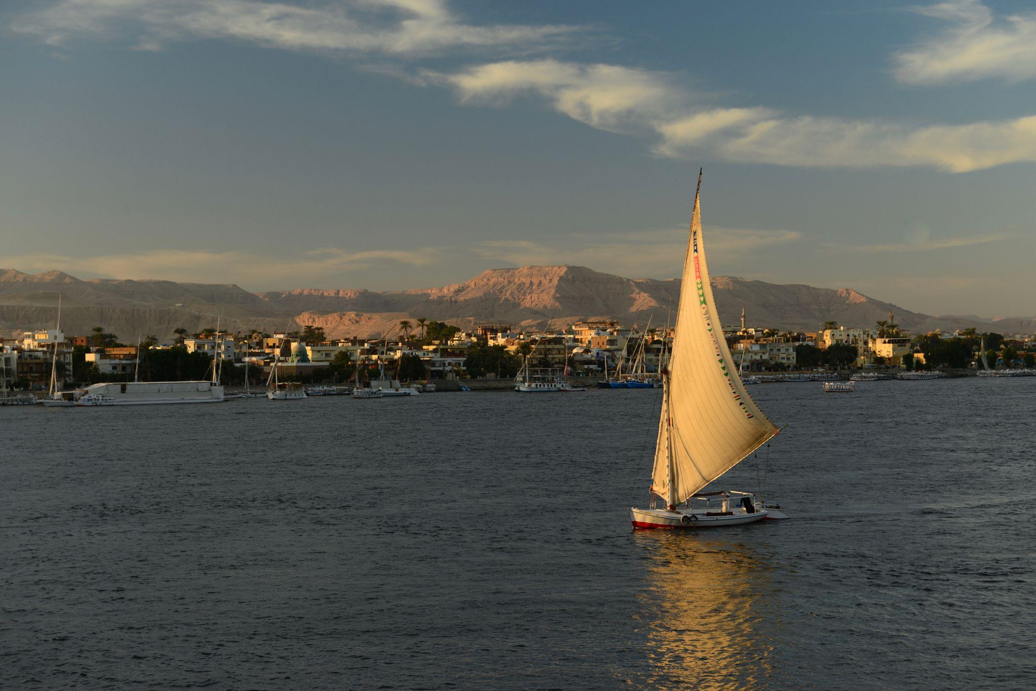 Felucca sailing on the Nile with Theban hills rising behind Luxor
