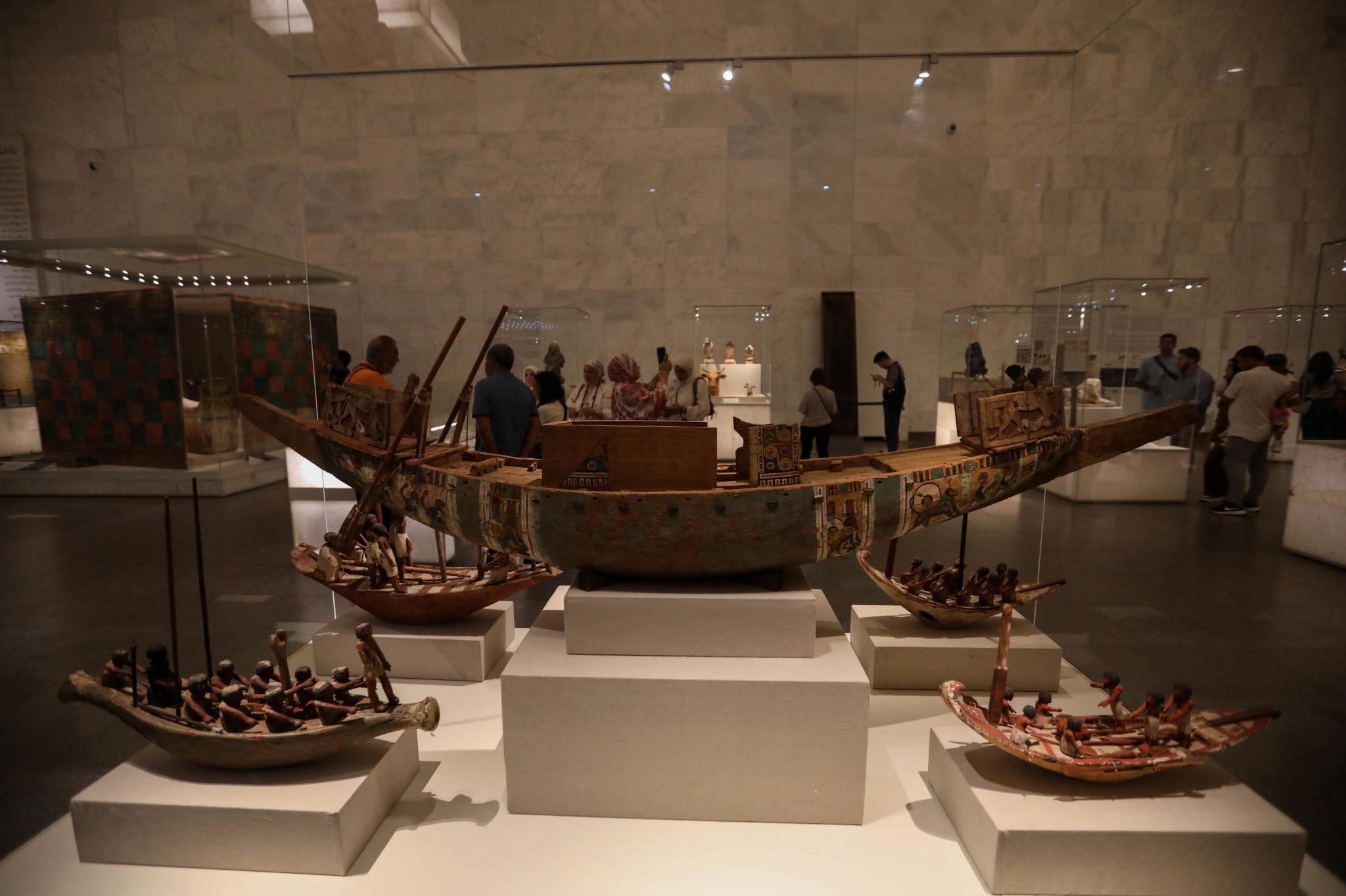 Ancient Egyptian wooden boat models with figurines on display at the NMEC museum gallery