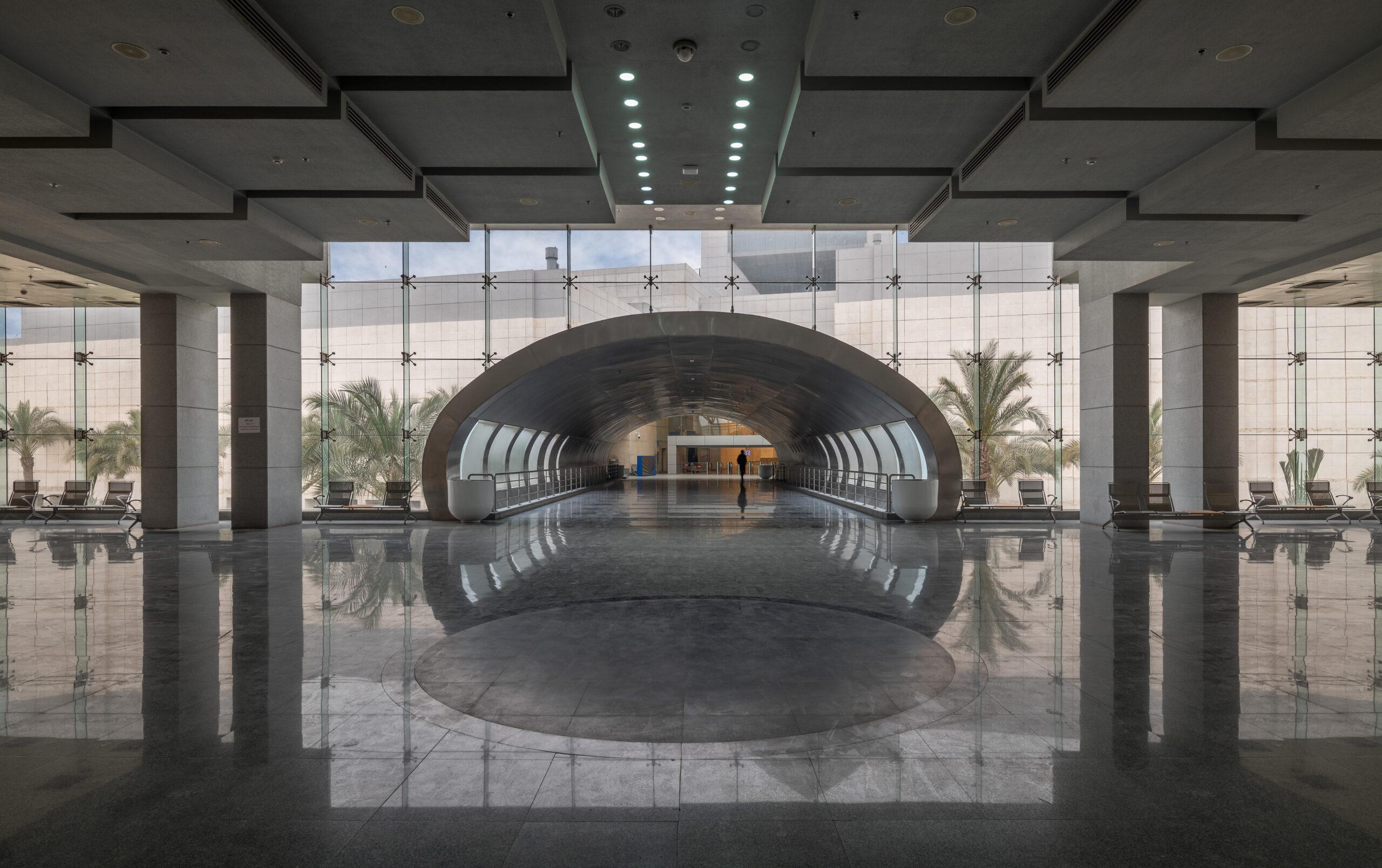 Sleek arched tunnel entrance reflected in polished marble floors of the NMEC lobby