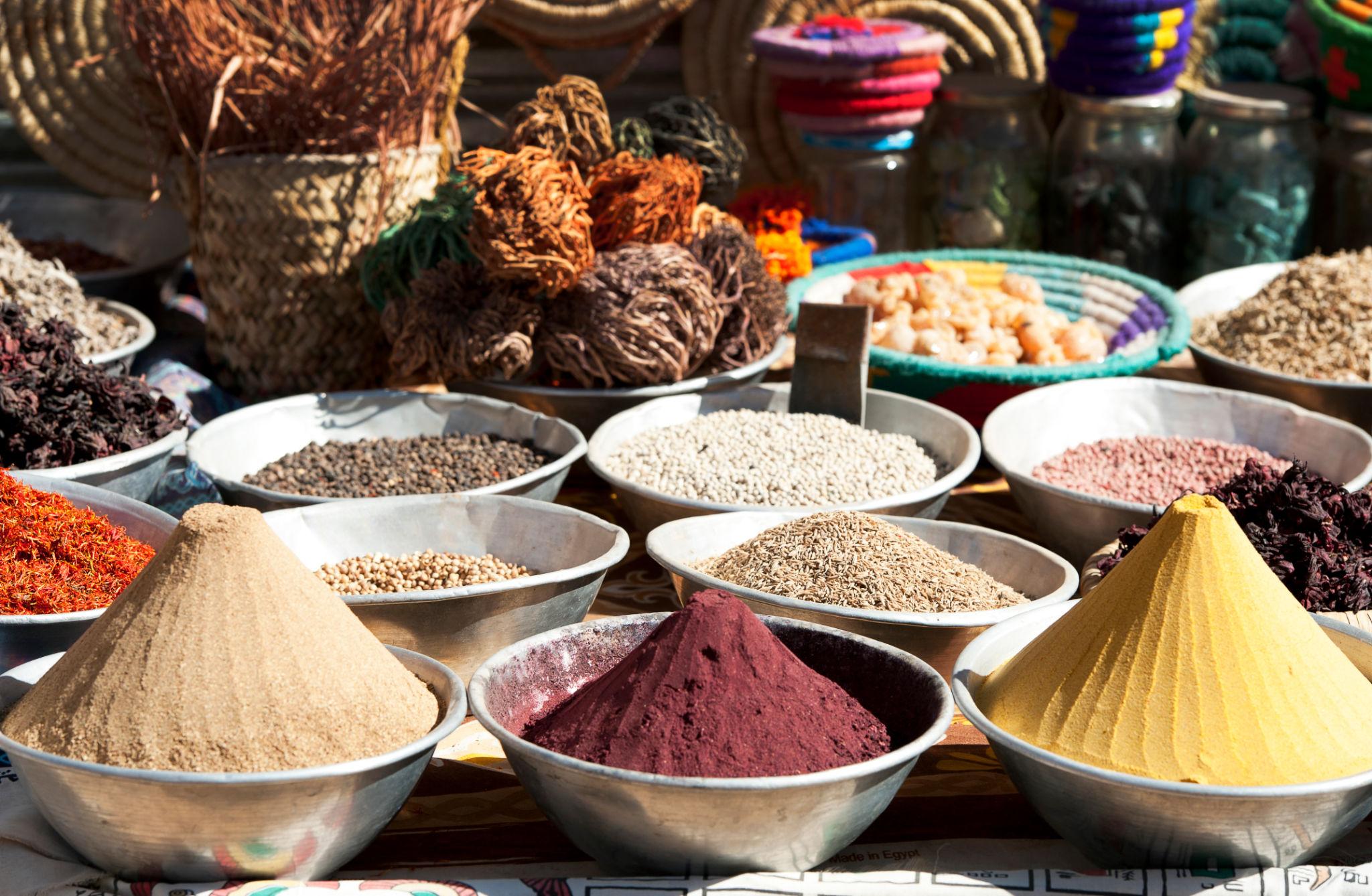 Vibrant mounds of ground spices and seeds displayed in silver bowls at an Egyptian market stall