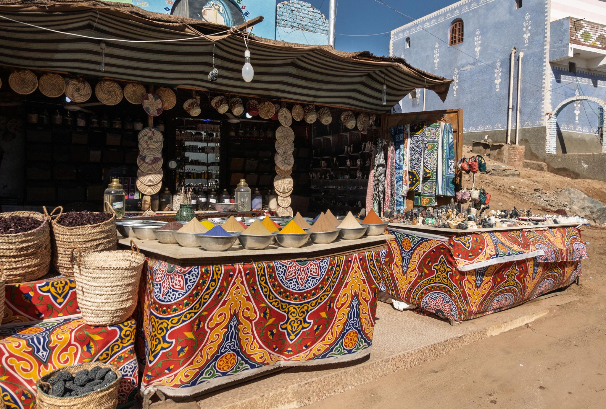 Vibrant Egyptian market stall with cone-shaped spices, woven baskets, and ornate fabric draping.