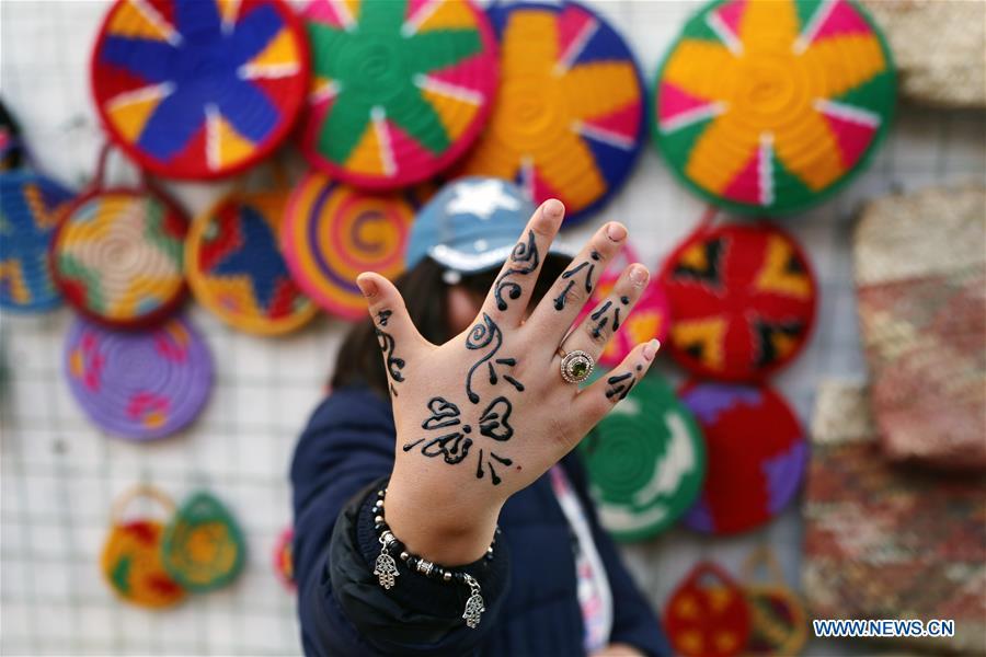 Hand with henna artwork raised before colorful Nubian woven baskets