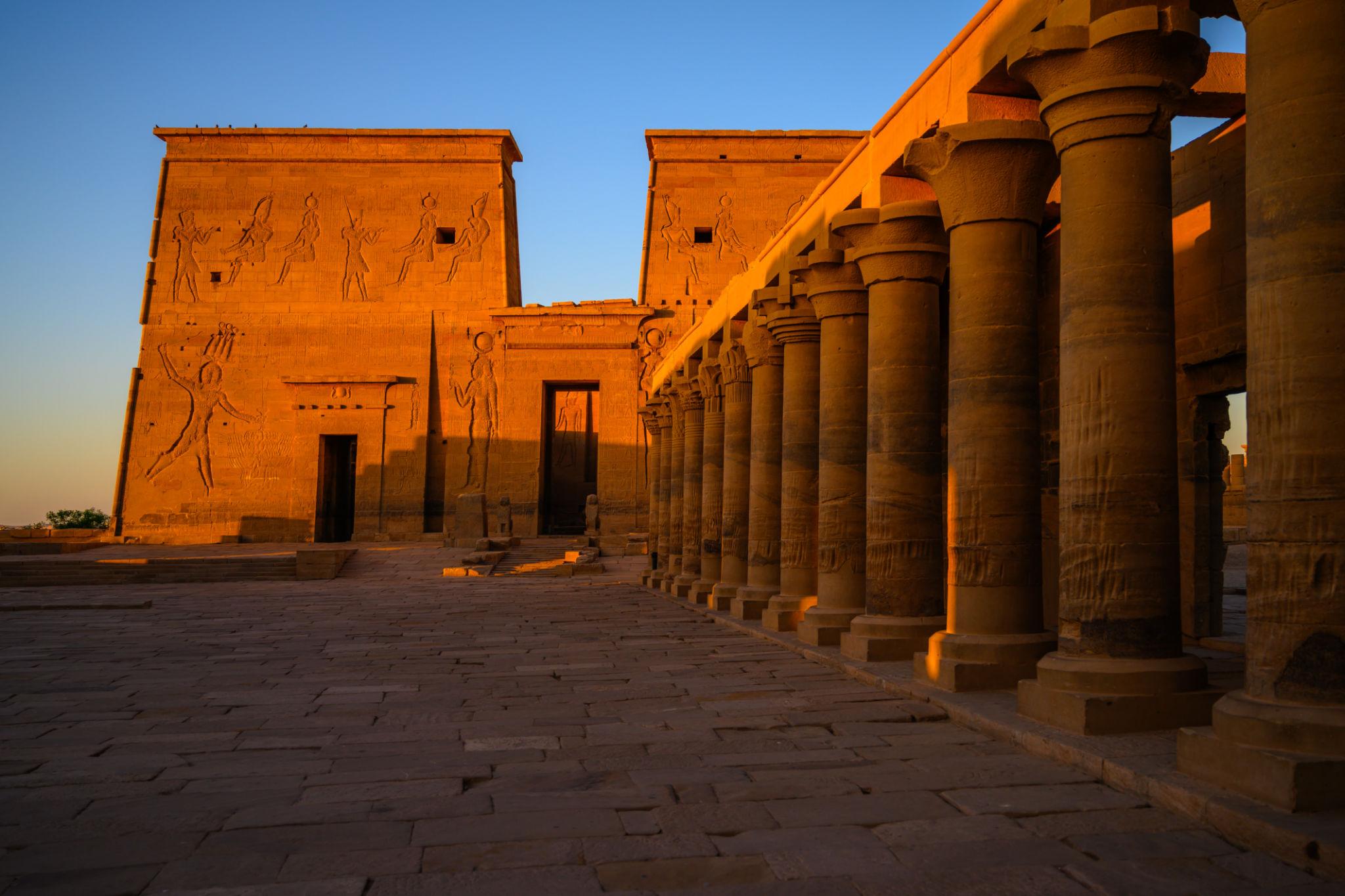 Philae Temple's carved pylons and colonnaded courtyard bathed in warm sunset light