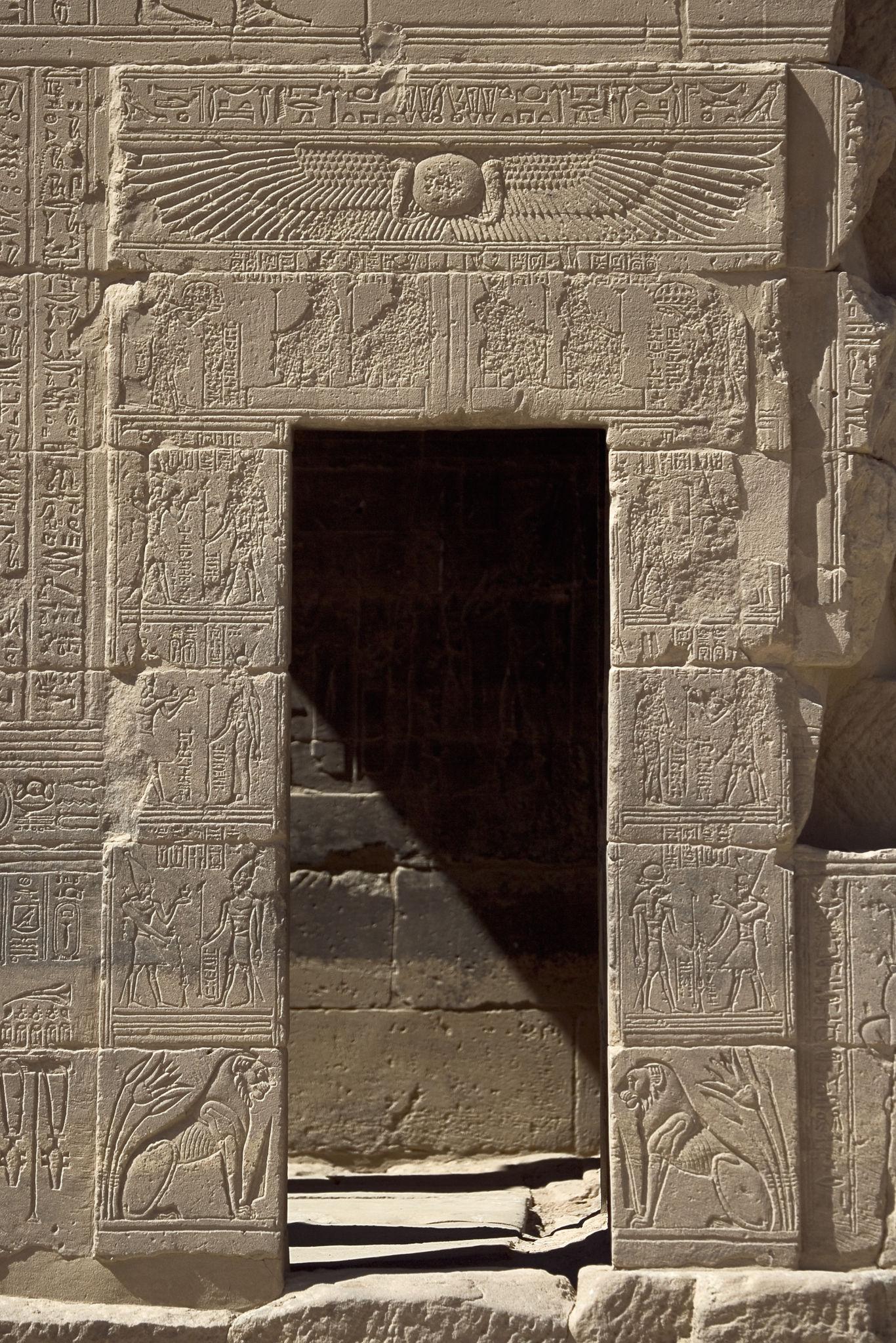 Ornate hieroglyph-covered stone doorway at Philae Temple leading into a dark interior chamber