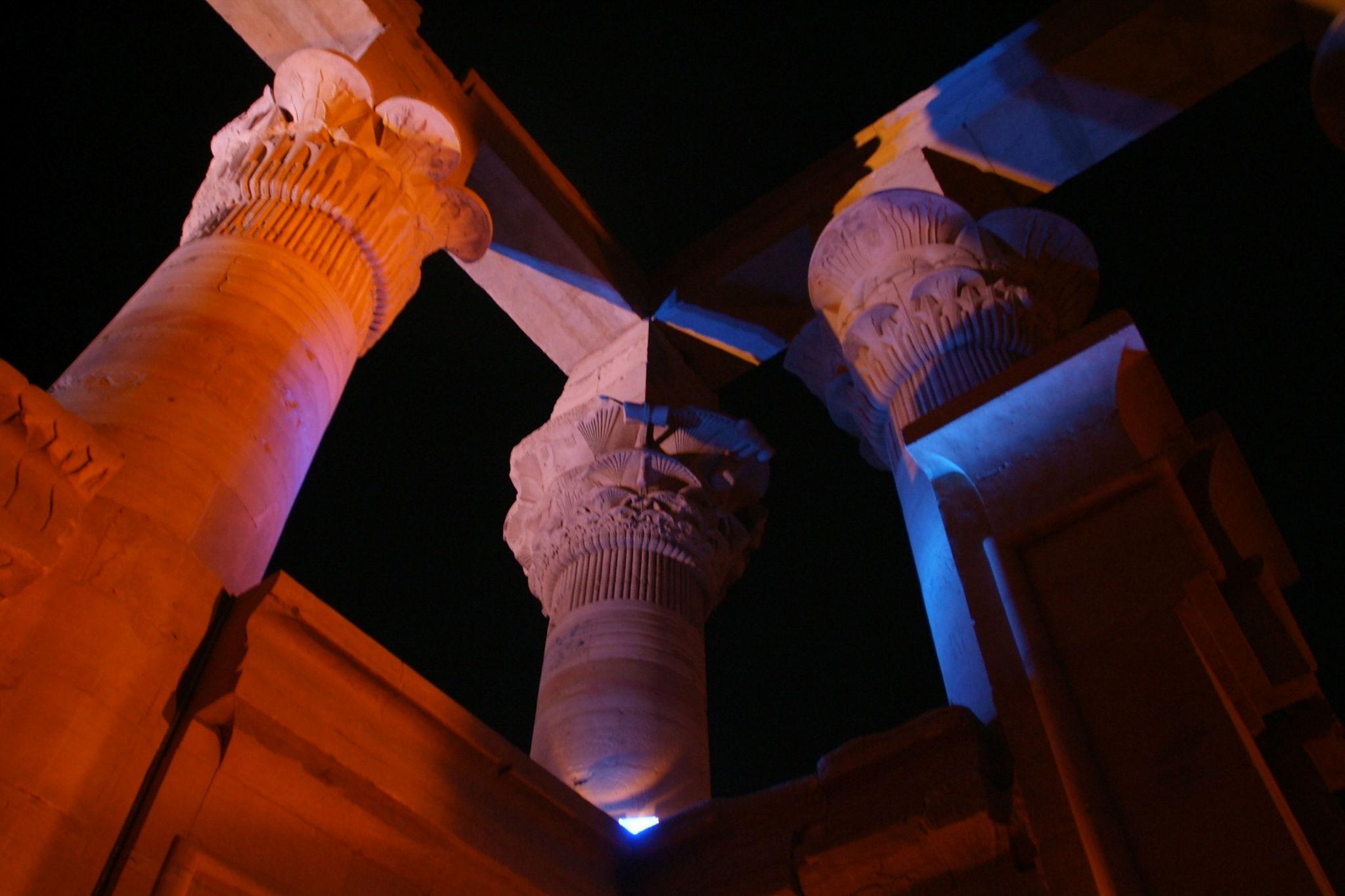 Ancient Egyptian papyrus columns at Philae Temple dramatically lit in orange and blue at night