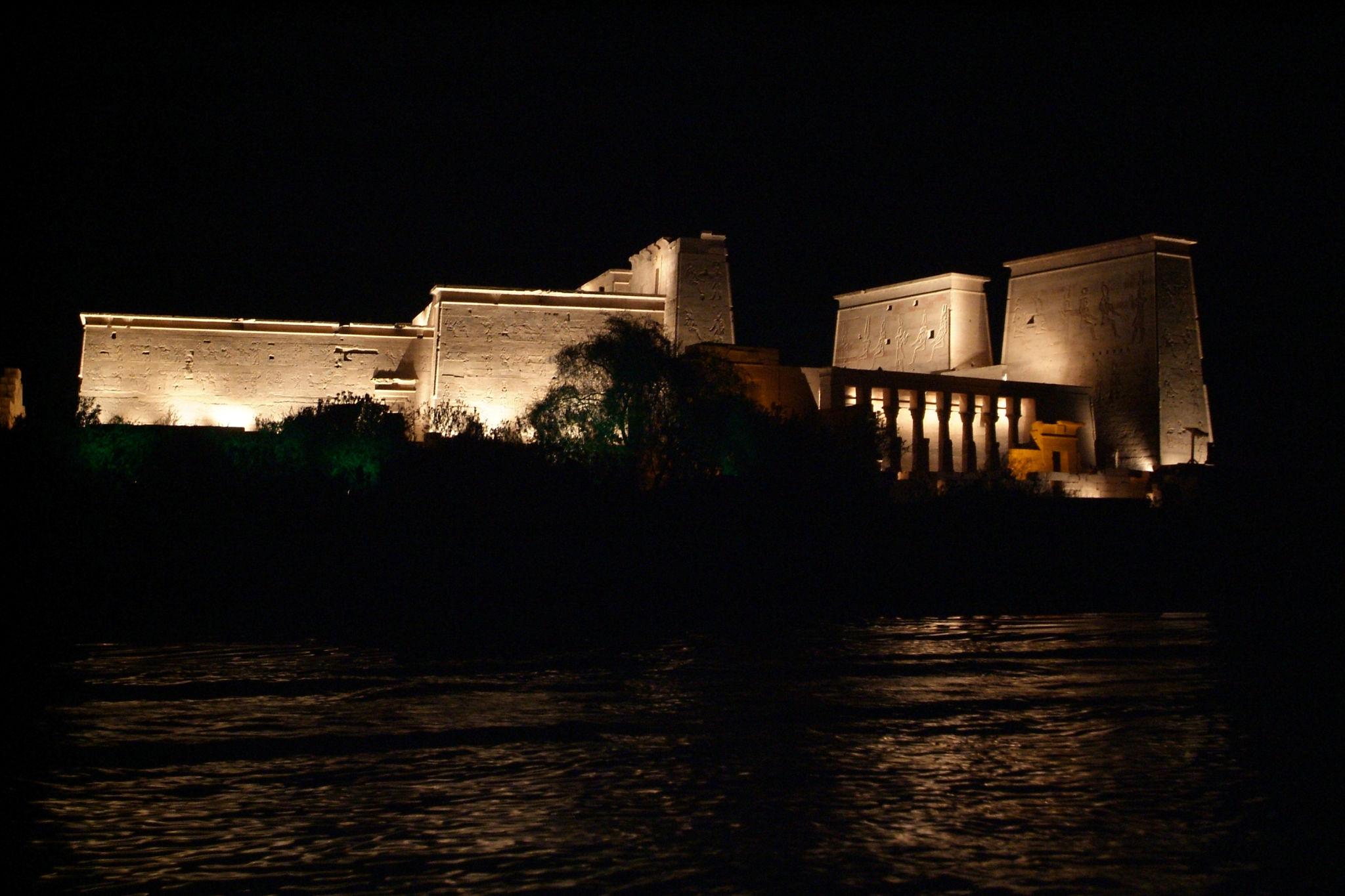 Philae Temple dramatically lit at night reflected in the dark waters of the Nile