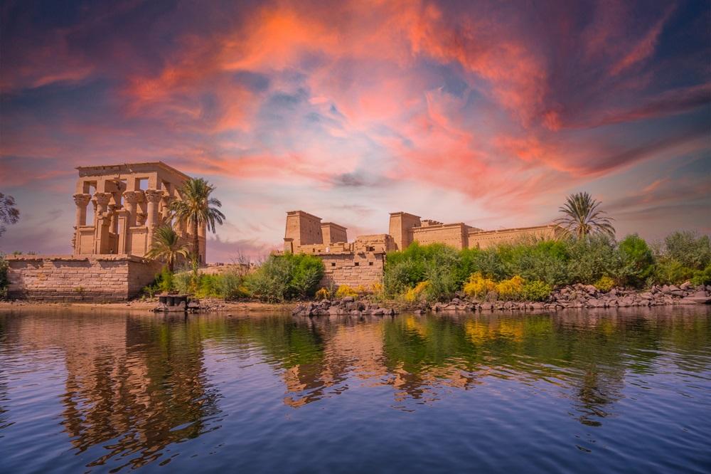 Philae Temple of Isis reflected in the Nile under a vivid pink and orange sunset sky