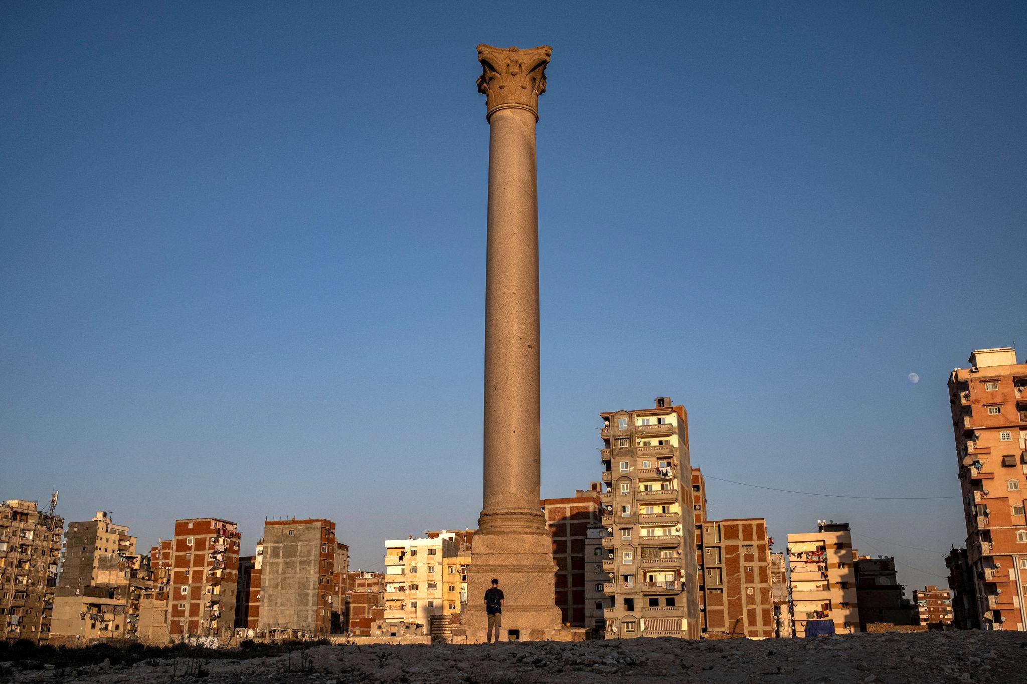 Pompey's Pillar standing tall above the Alexandria cityscape at sunset