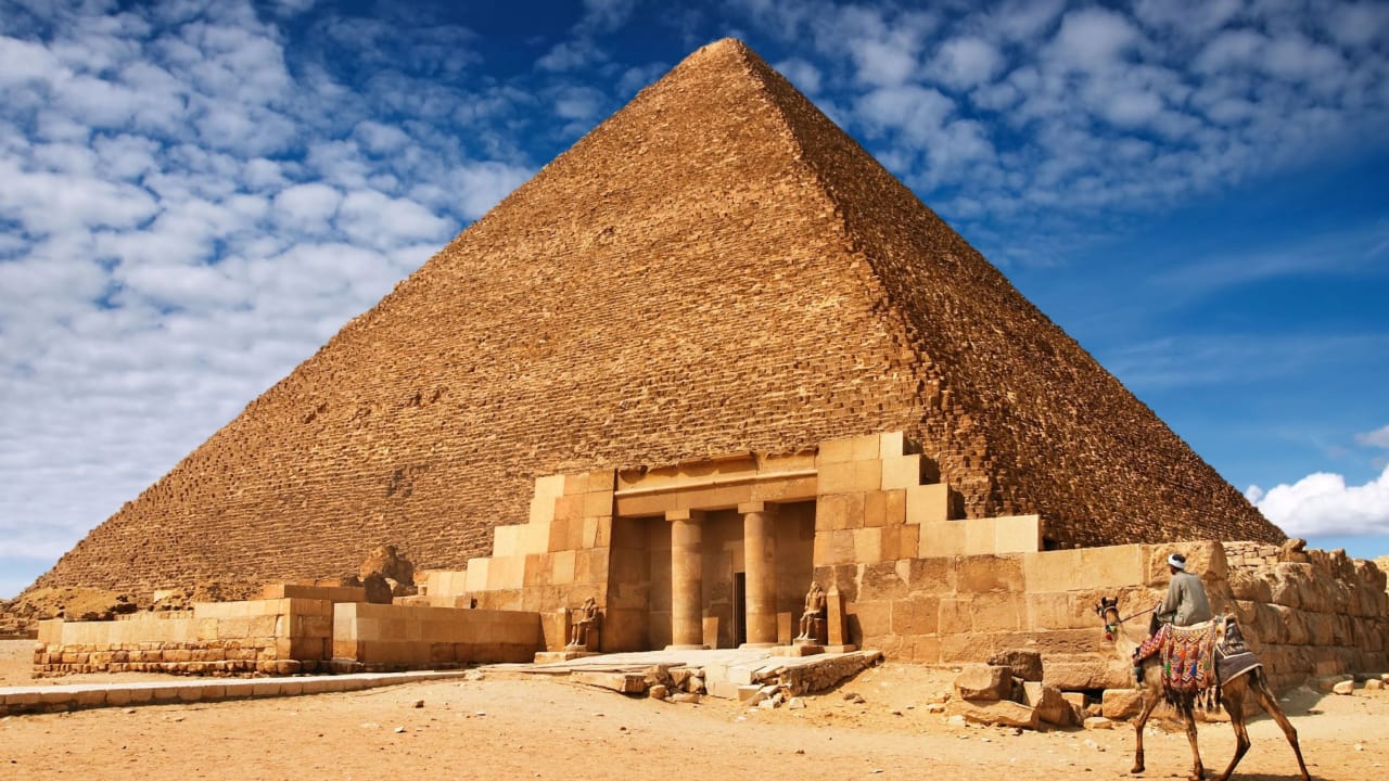 Great Pyramid of Khufu entrance with a camel rider approaching the ancient stone blocks