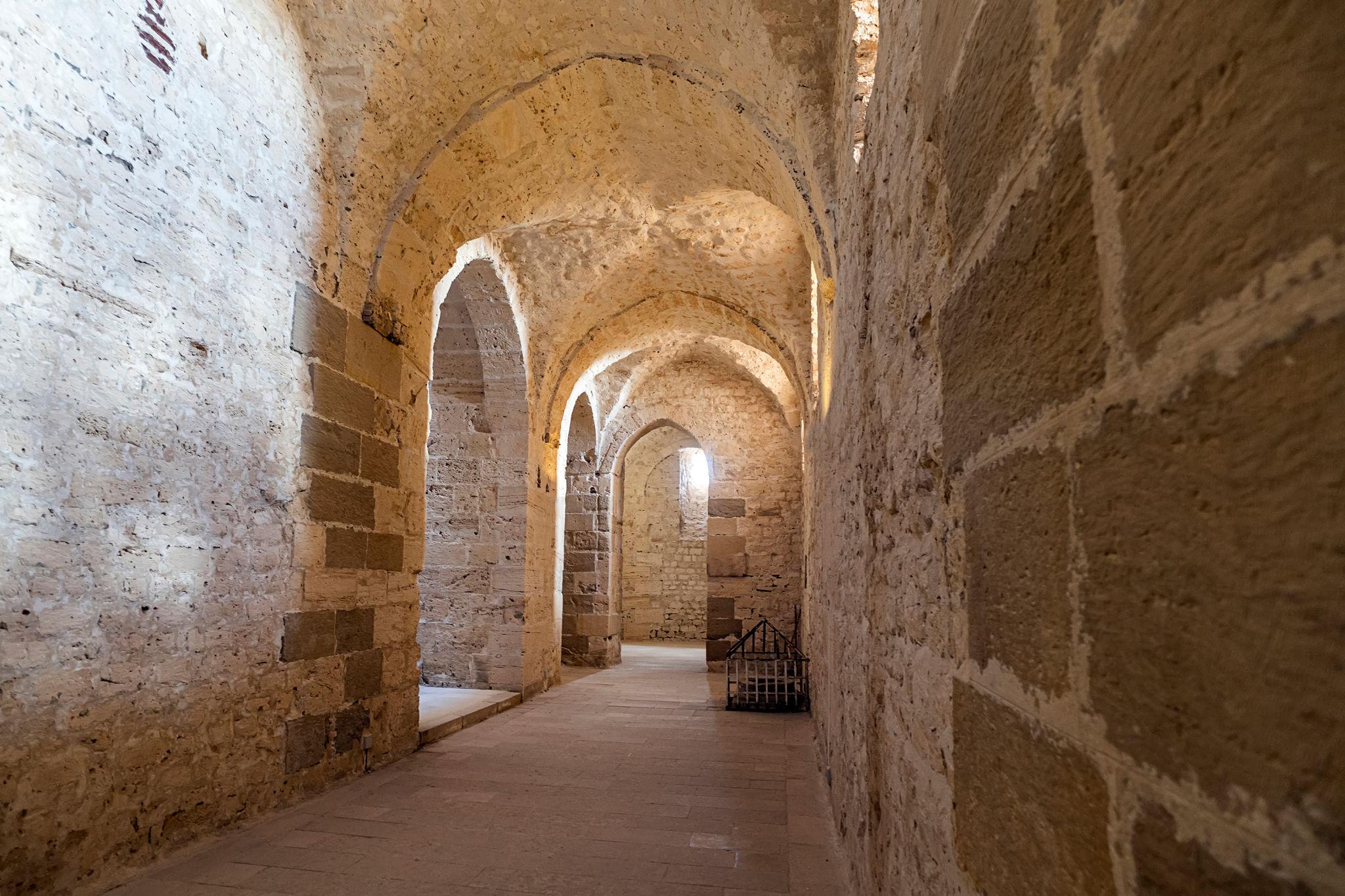 Vaulted stone corridor inside Qaitbay Citadel with arched passageways and limestone walls