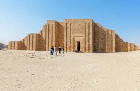 Tourists walk before the massive ancient stone enclosure wall of Saqqara in the Egyptian desert.