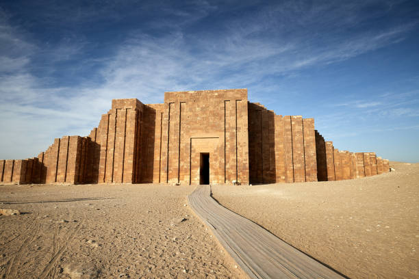 Massive ancient stone enclosure wall with tall pylons at Saqqara under a blue sky