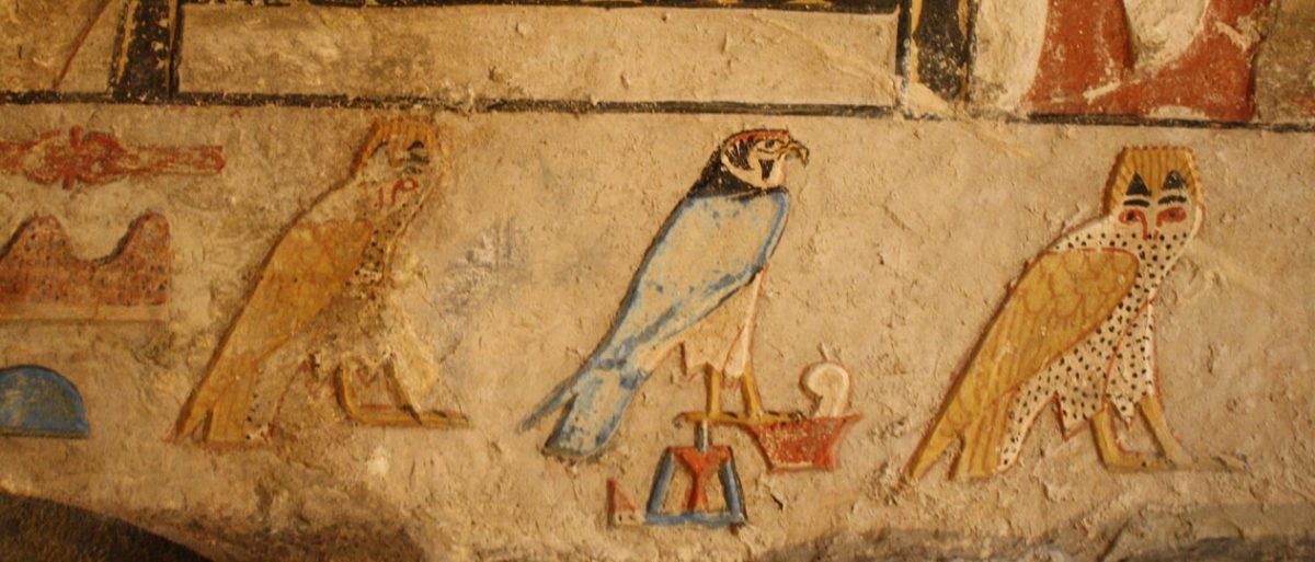 Colorful ancient Egyptian painted falcons and hieroglyphs on a tomb wall at Saqqara
