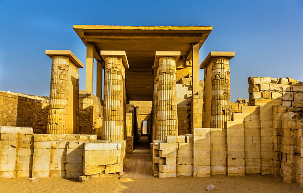 Ancient Egyptian fluted stone columns lining an entrance corridor at Saqqara under blue sky