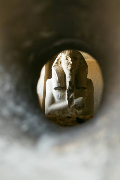 Ancient Egyptian seated statue framed through a circular tunnel opening at the Serapeum of Saqqara