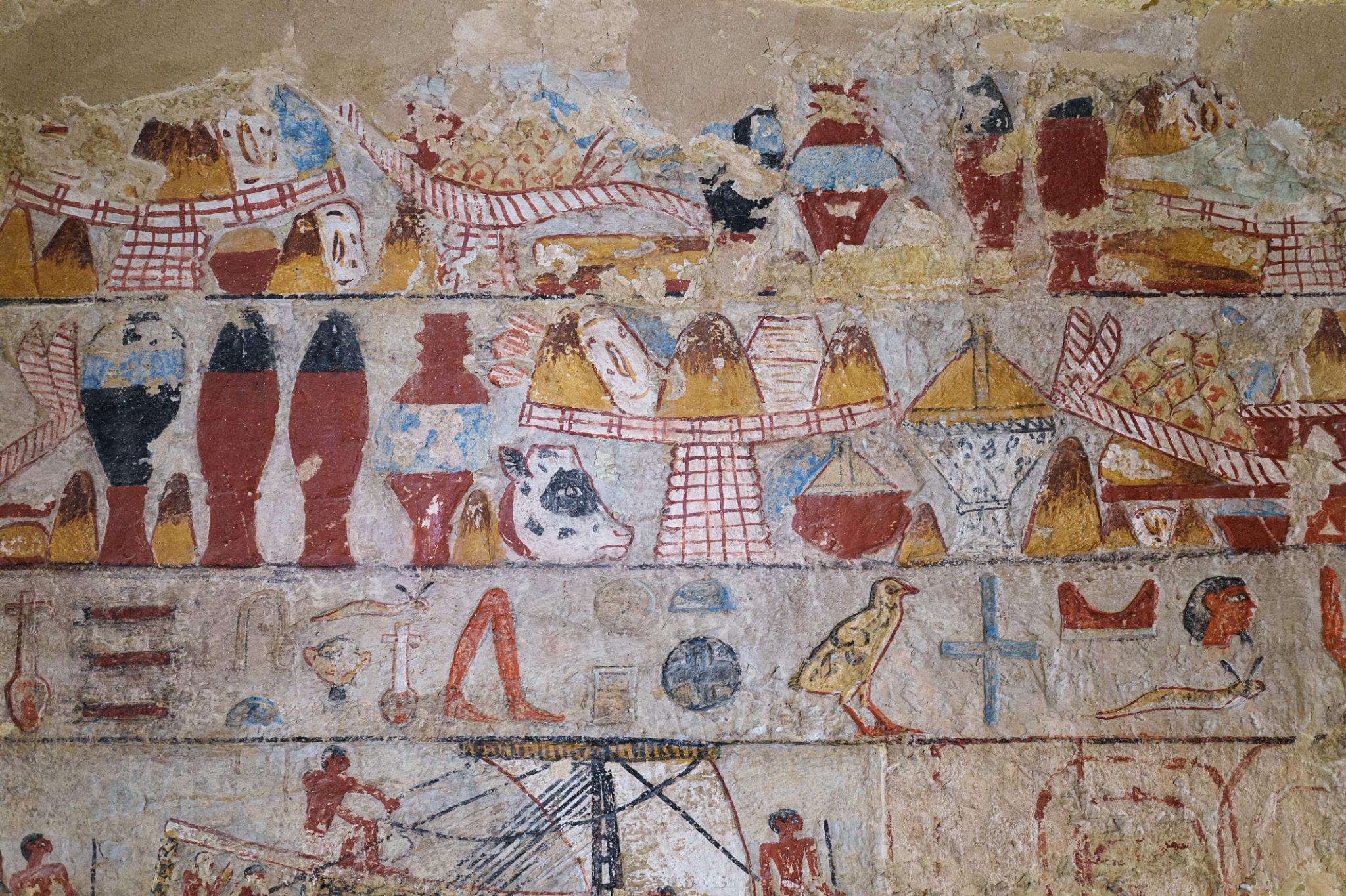 Colorful ancient Egyptian tomb wall painting showing registers of offerings, vessels, and hieroglyphs