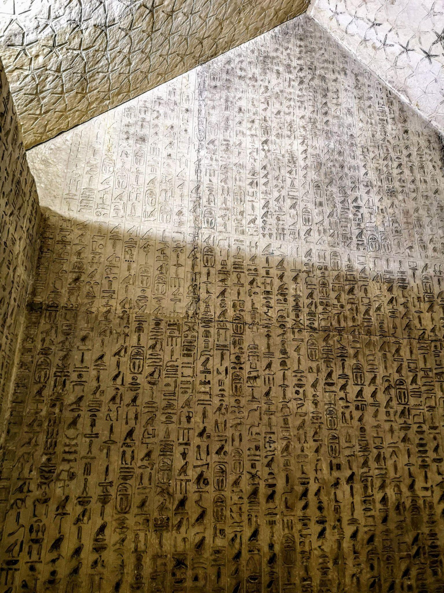 Ancient Egyptian hieroglyphic Pyramid Texts densely carved across limestone chamber walls