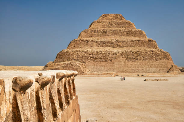 Cobra frieze wall in foreground with the Step Pyramid of Djoser rising behind it at Saqqara