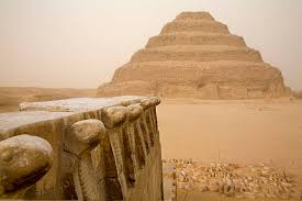 The Step Pyramid of Djoser rises behind ancient stone ruins at Saqqara in dusty haze