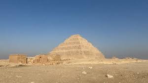 The Step Pyramid of Saqqara rises above the desert plain under a clear blue sky.