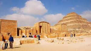 Tourists exploring the ancient courtyard and Step Pyramid of Saqqara under a clear sky