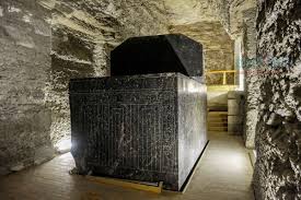 A massive black granite sarcophagus inside the dimly lit underground chambers of the Serapeum.