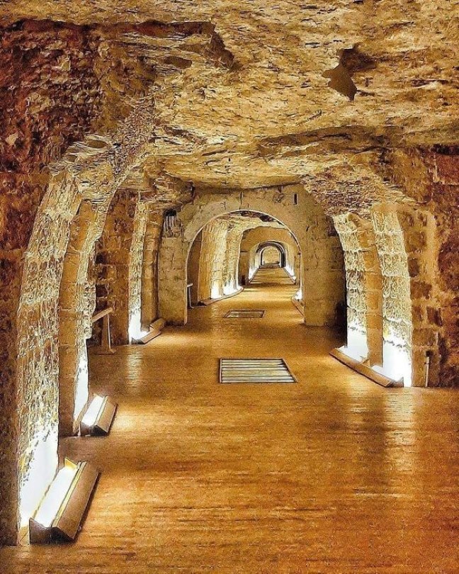 Illuminated stone arched tunnel corridor inside the Serapeum of Saqqara, Egypt