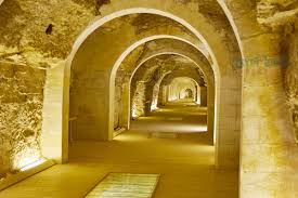 Illuminated ancient stone corridor with arched vaults stretching into the distance at Saqqara