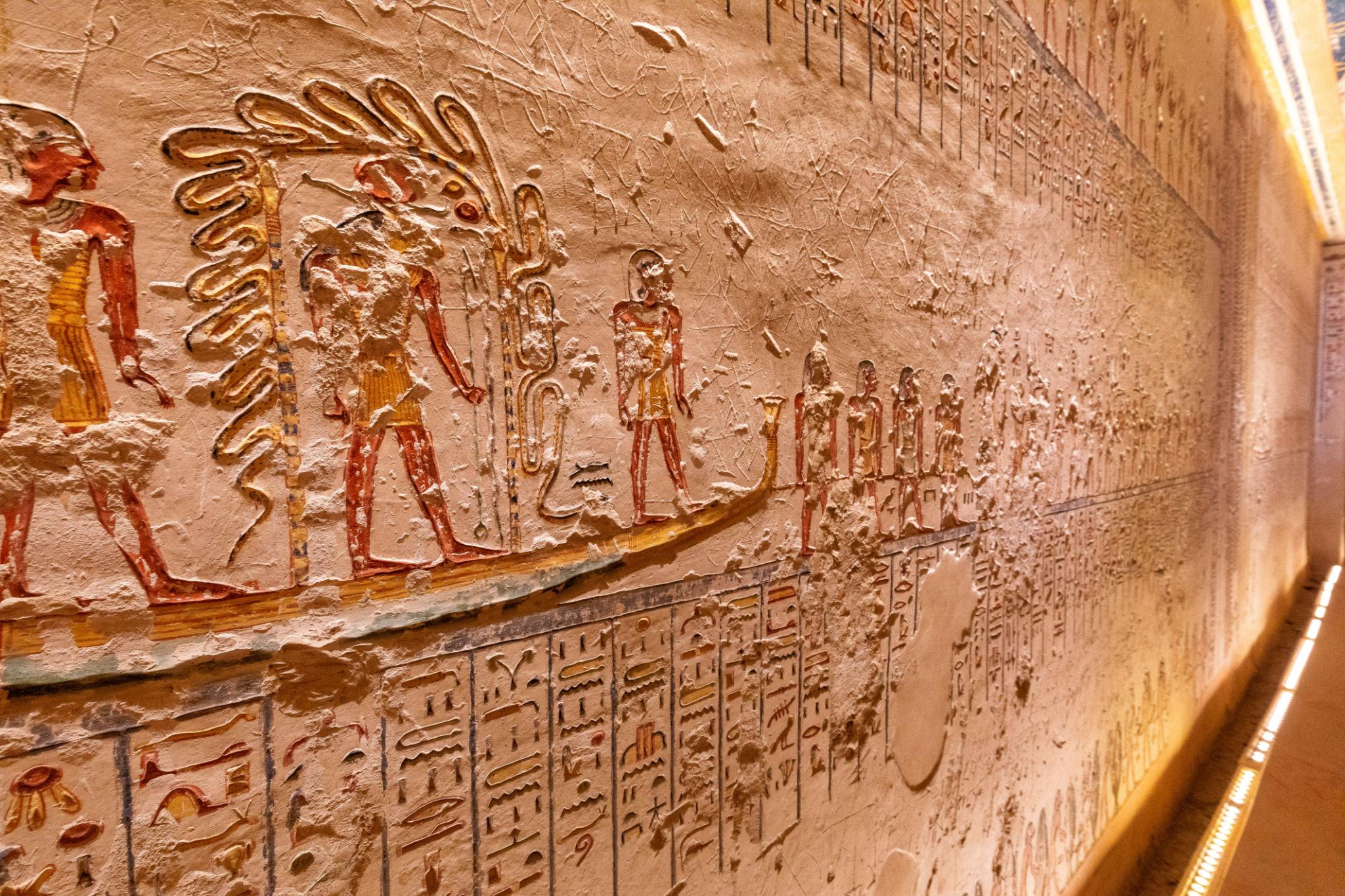 Carved and painted relief of processional figures above bands of hieroglyphs.