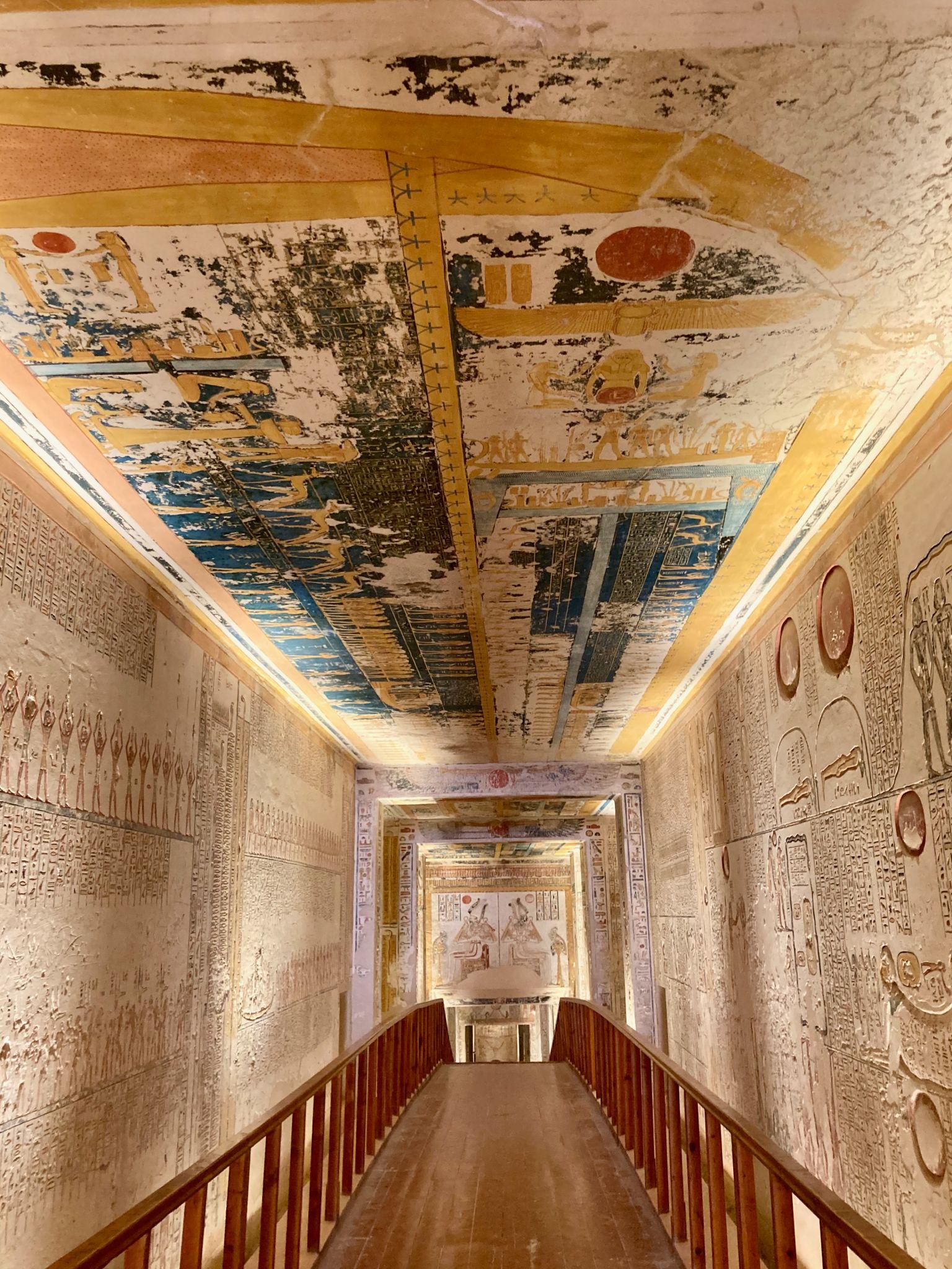 Long decorated tomb corridor with painted ceiling and hieroglyph-covered walls.