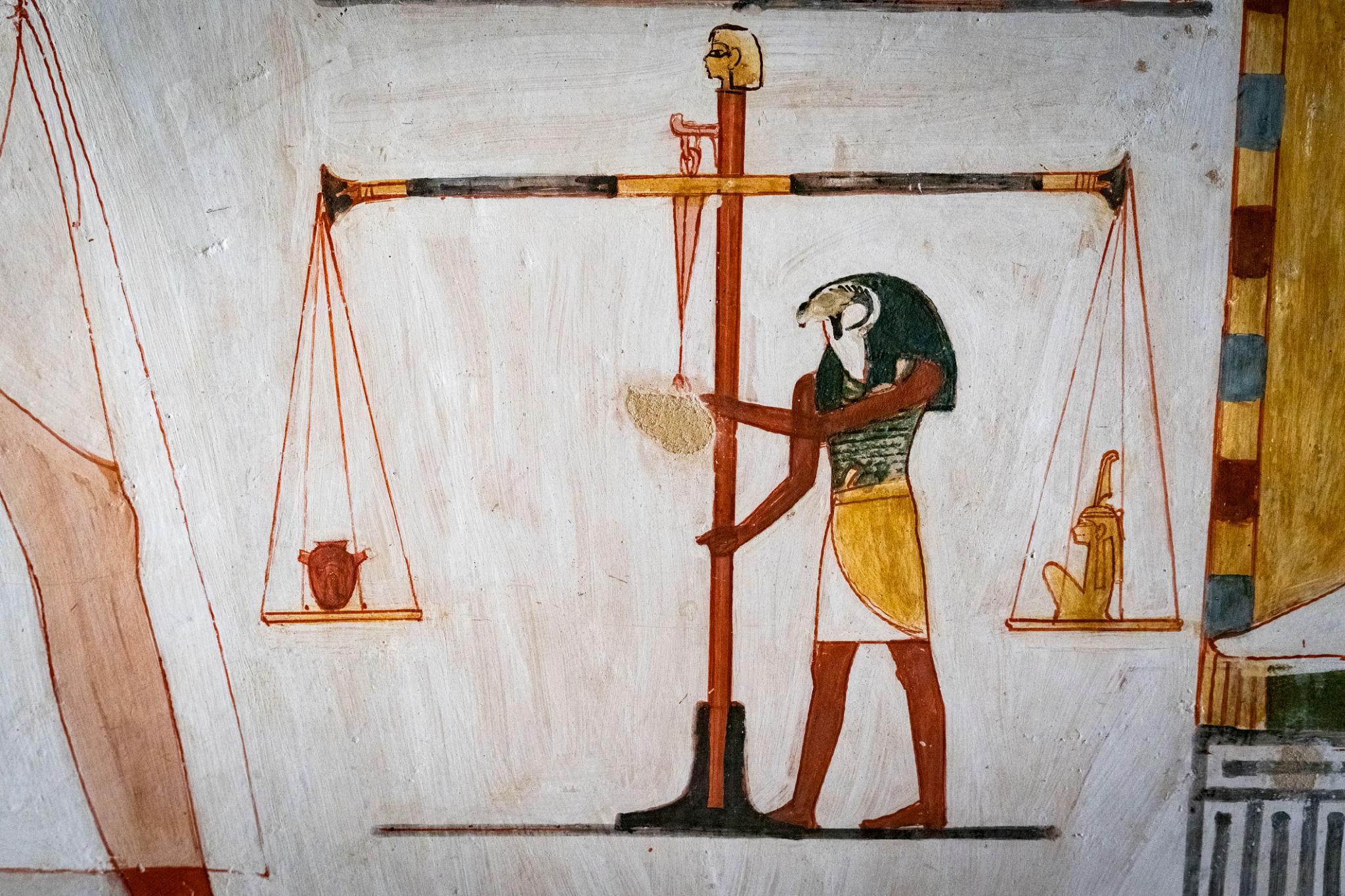 Painted Thoth operating the scales of judgement in a tomb wall scene.